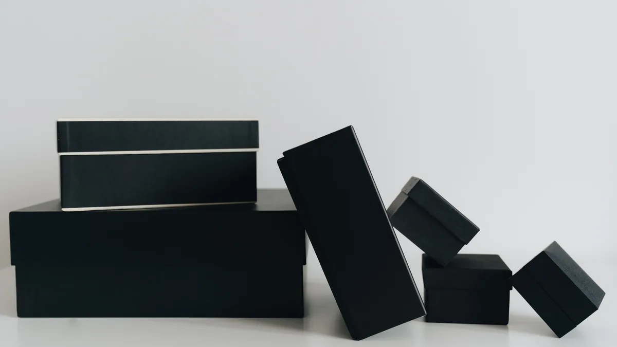 Sechs schwarze Geschenkschachteln in verschiedenen Größen vor hellem Hintergrund