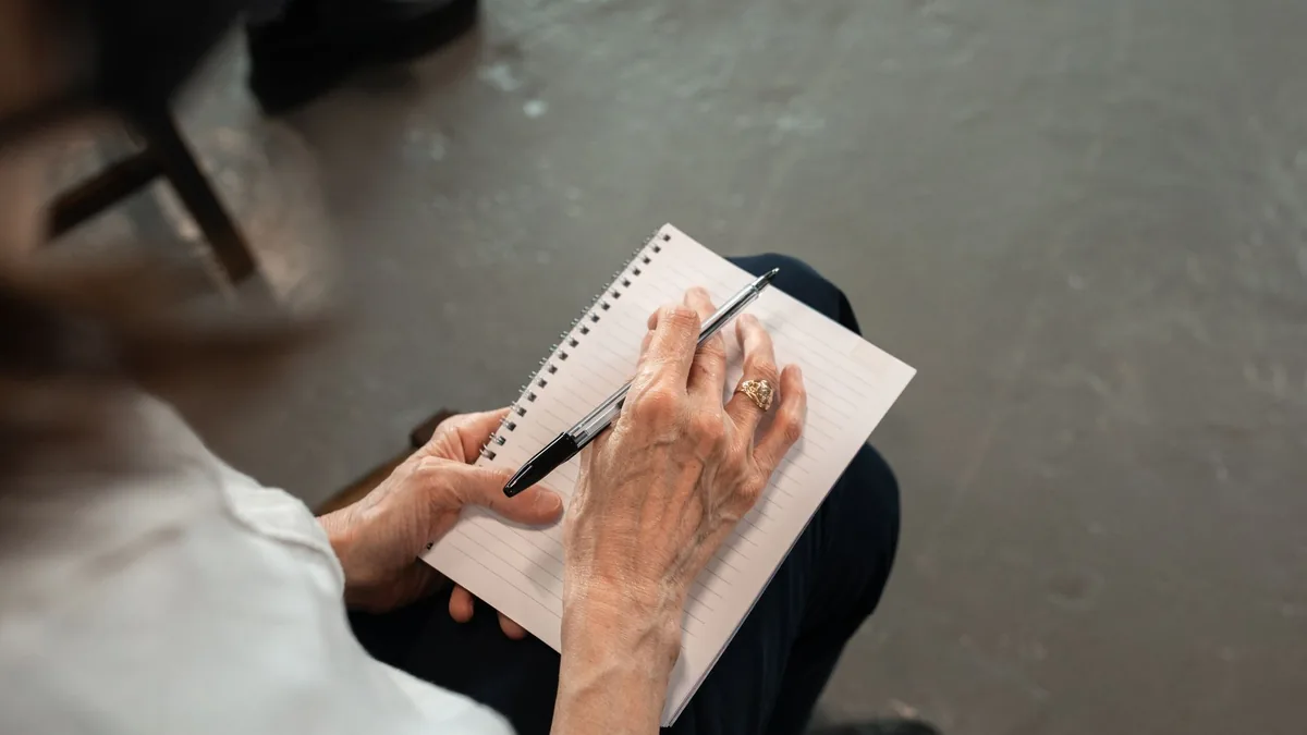 Hände schreiben mit einem Stift in ein Notizbuch