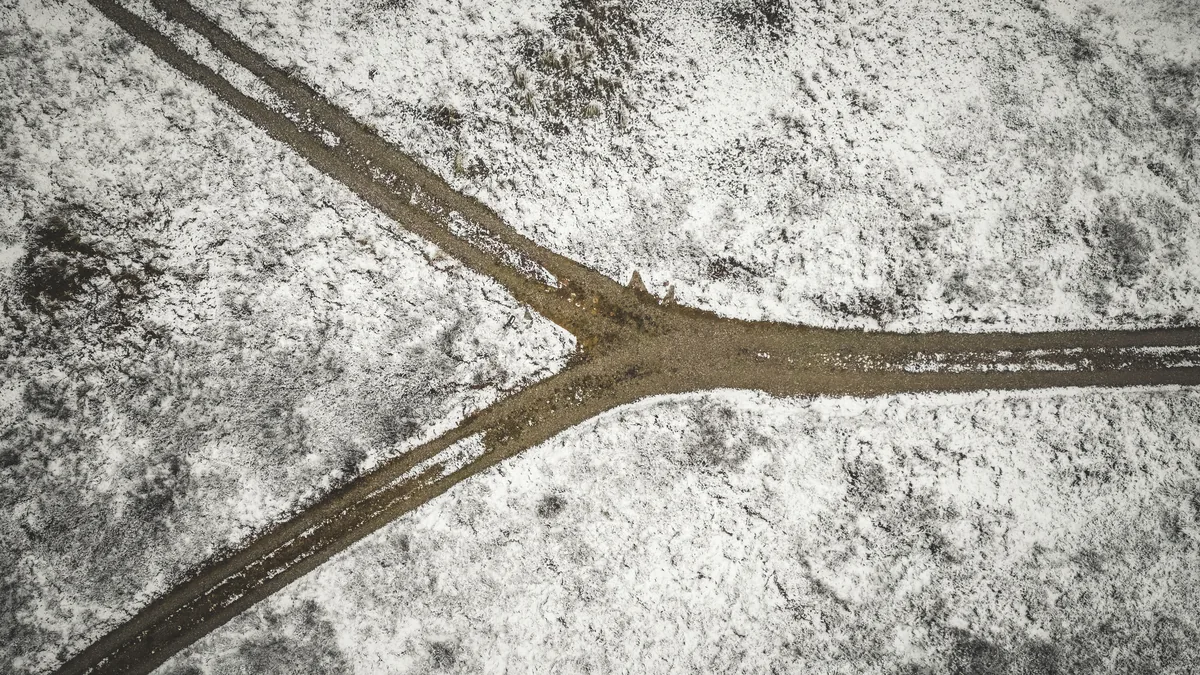 Luftbild eines verschneiten Feldes, in dem sich ein Feldweg in zwei Richtungen gabelt